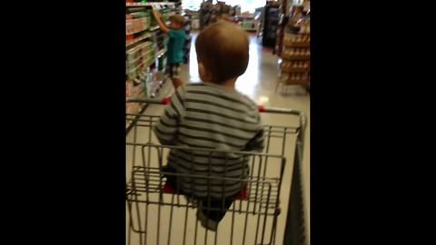 "Tot Boy Dances In A Shopping Cart In A Store"