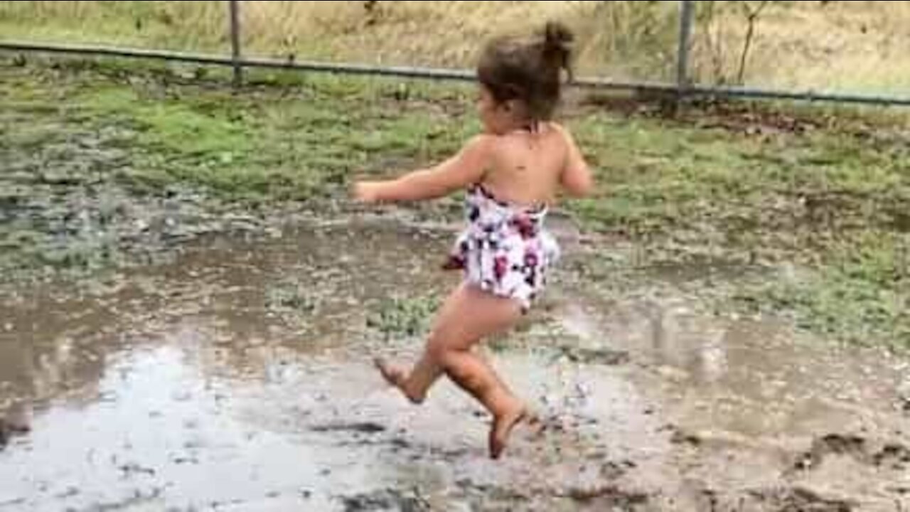 Cette petite fille s'amuse avec une flaque de boue