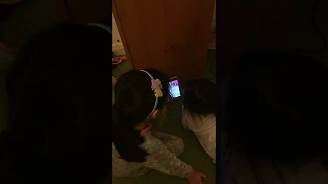 Sweet little girls are watching on daddy's phone and giggling happy