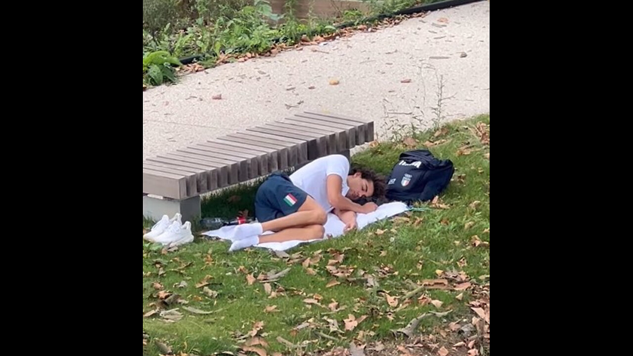 Italian gold medal-winning swimmer Thomas Ceccon sleeping next to park bench.