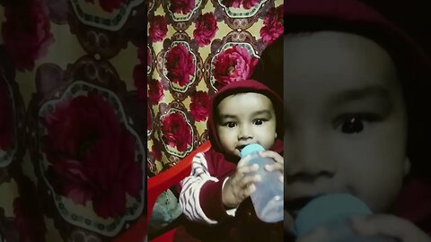 a cute baby boy playing with feeding bottle