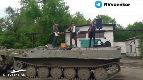 A DNR fighter sings and plays along with Russian singer Django on an MTLB at frontline Makiivka