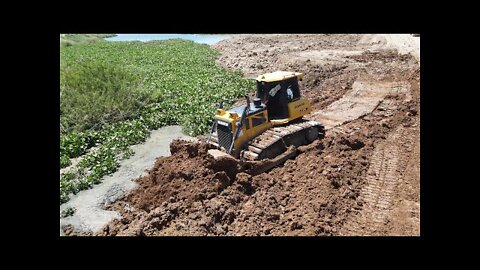 New mighty bulldozer pushing dirt in land reclamation construction on the lake