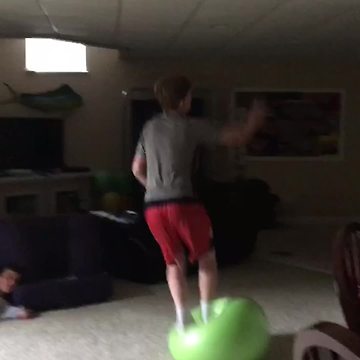 A Teen Boy Jumps On Yoga Ball And Falls