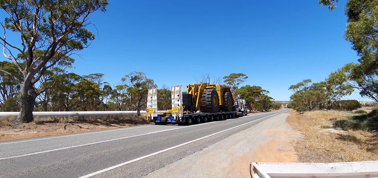 Volvo with lowboy low loader hauling oversize load CAT 993k wheel loader min