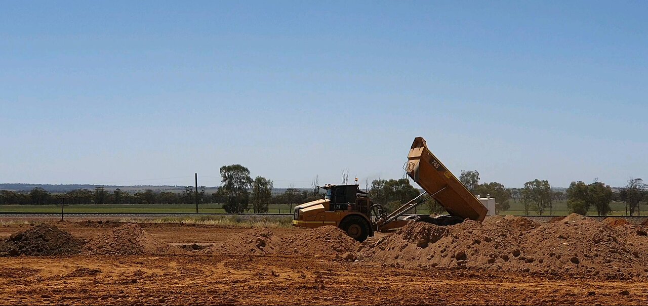 Earthworks for grain storage facility: excavator, articulated dump truck, water truck, bull dozer