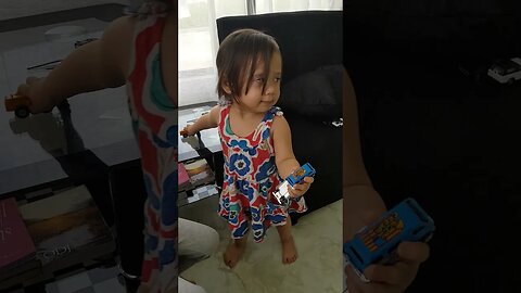 Baby girls are playing with cars while their grandfather watches