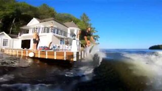 Raggiunge una barca cavalcandone l'onda con una tavola da surf