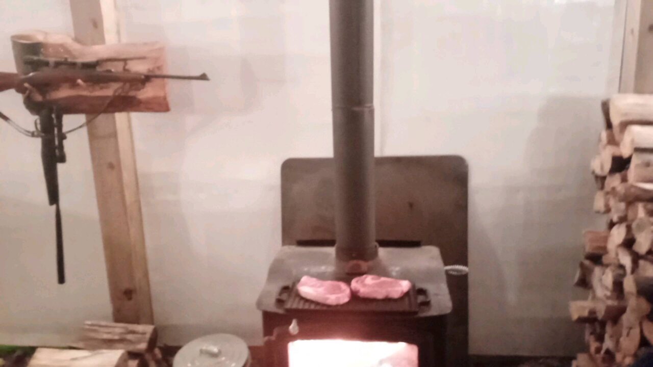 Wood stove cooking steaks.