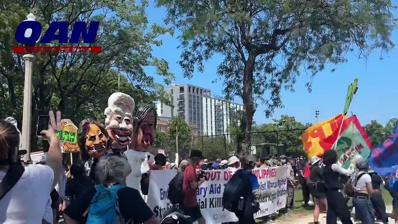 Depictions of Antony Blinken, Biden, & Harris are paraded around the park