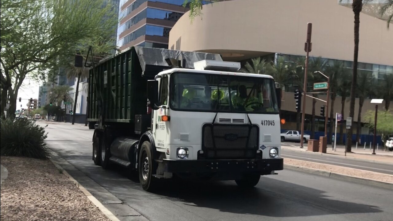 Waste Management roll off truck driving bye.