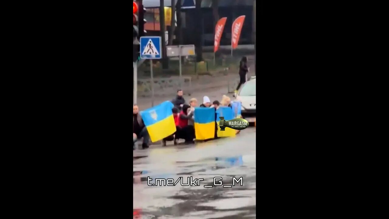 Ukrainian cirizens kneel as funeral of fallen soldier passes by