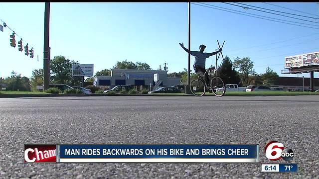 Man rides backward on bike to bring cheer