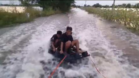 Vänner åker wakeboard på översvämmade gator i Thailand