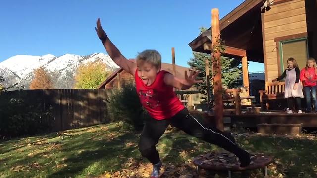 Young Boy Jumps Off A Trampoline Into A Pile Of Leaves