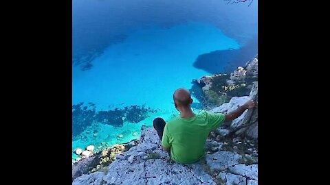 Man sits over edge of beautiful scenery....