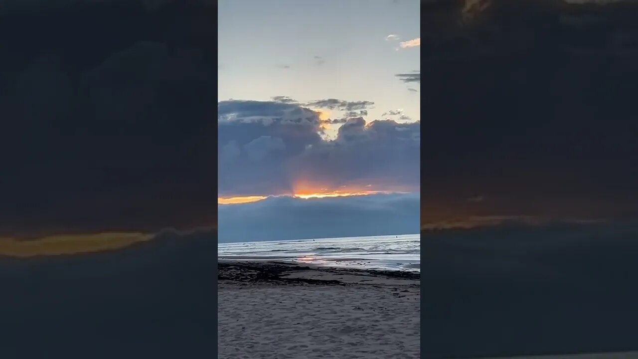 Sun peeking through two clouds