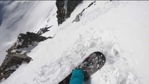 Snowboarder films downhill descent on slope