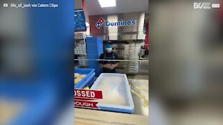 Un employé de Domino’s Pizza prépare une pizza les yeux bandés