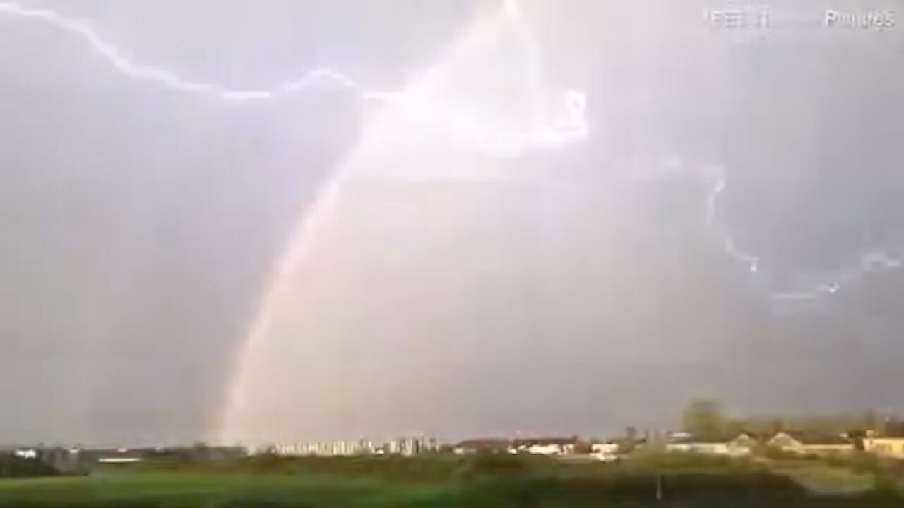 Lightning flashed near a rainbow over a residential area [Mysterious].