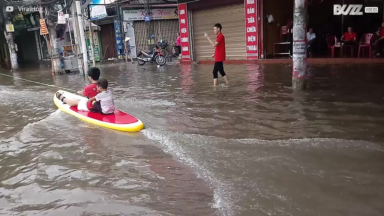 Bambini fanno surf in una strada allagata in Vietnam