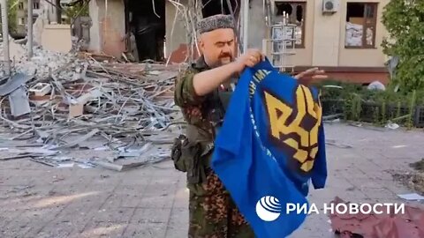 Un officier de la milice de Lougansk exhibe les drapeaux des régiments ukrainiens pris à l'ennemi