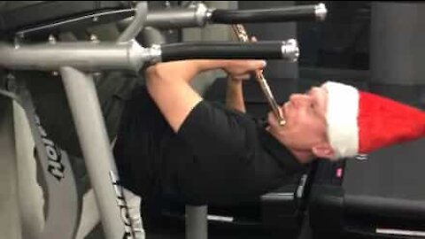 Mand i nissehue laver pull-ups, mens han spiller fløjte
