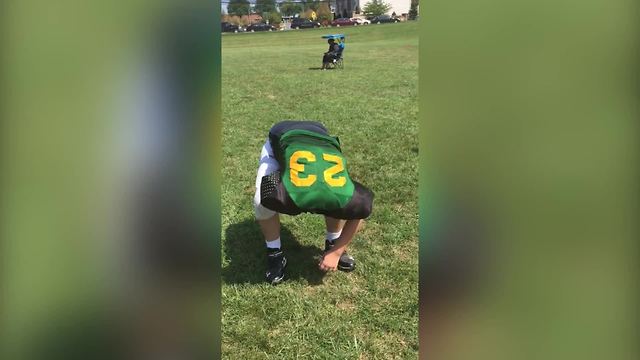 "A Young Boy Struggles to Get Out of A Football Jersey"