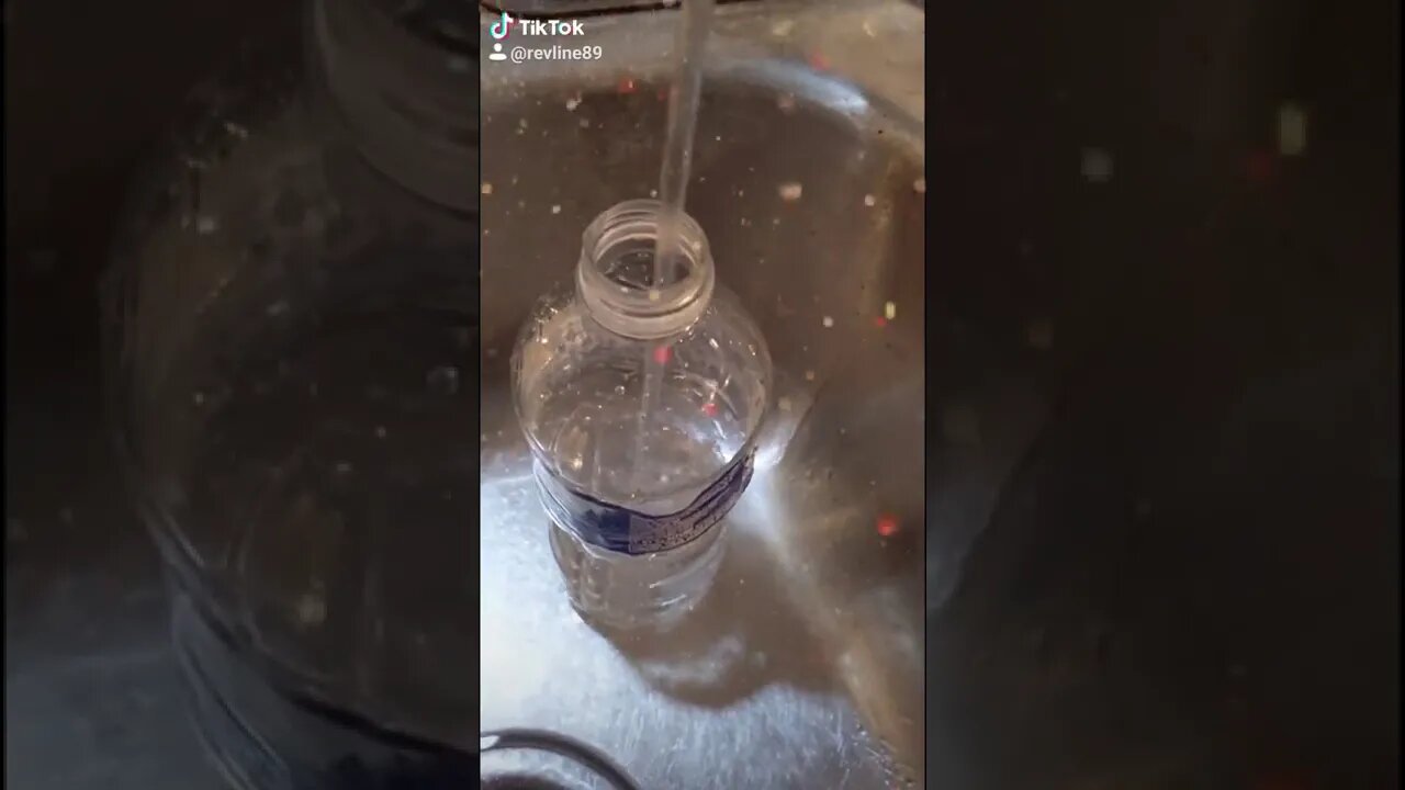 Filling a water bottle with drinking water