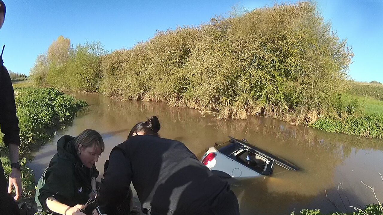 Police officers save woman stranded in her car from flooded ford