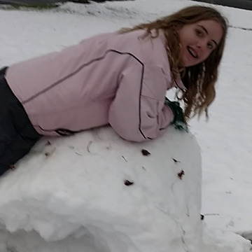 A Girl Rolls Snow Like It's Hay