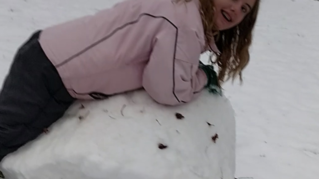 A Girl Rolls Snow Like It's Hay