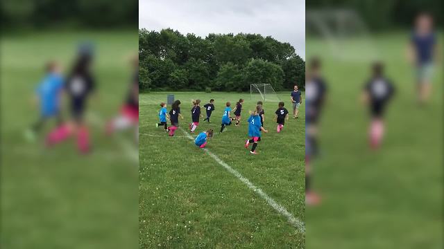 A Tot Girl Ignores A Soccer Game Being Played Around Her