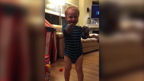 A Tot Boy Wears Socks On His Hands While He’s Picking Up His Toys