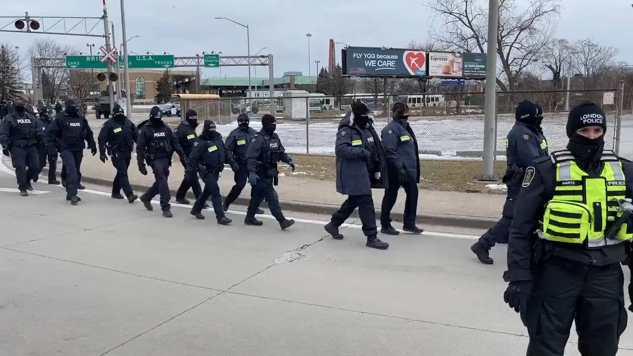 Police, some in military-style gear, move in to remove the protesters blocking the US-Canada border