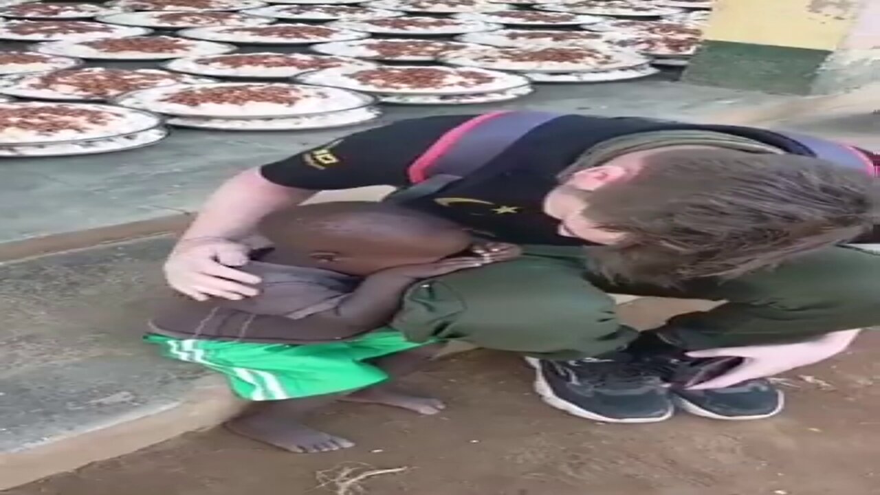 White man comforts heart broken african baby