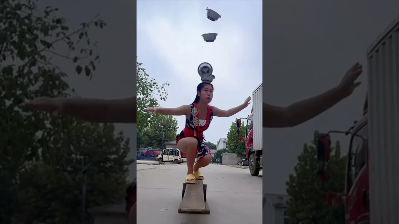 Chinese Girl Can Balance Herself And Catch Bowls On Her Head