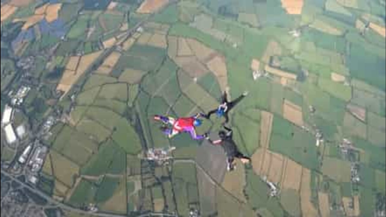 Friends hold onto each other while skydiving