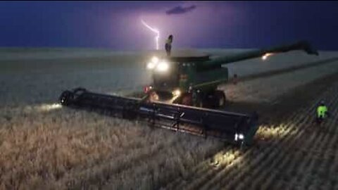 Un homme danse sur sa moissonneuse pendant un orage