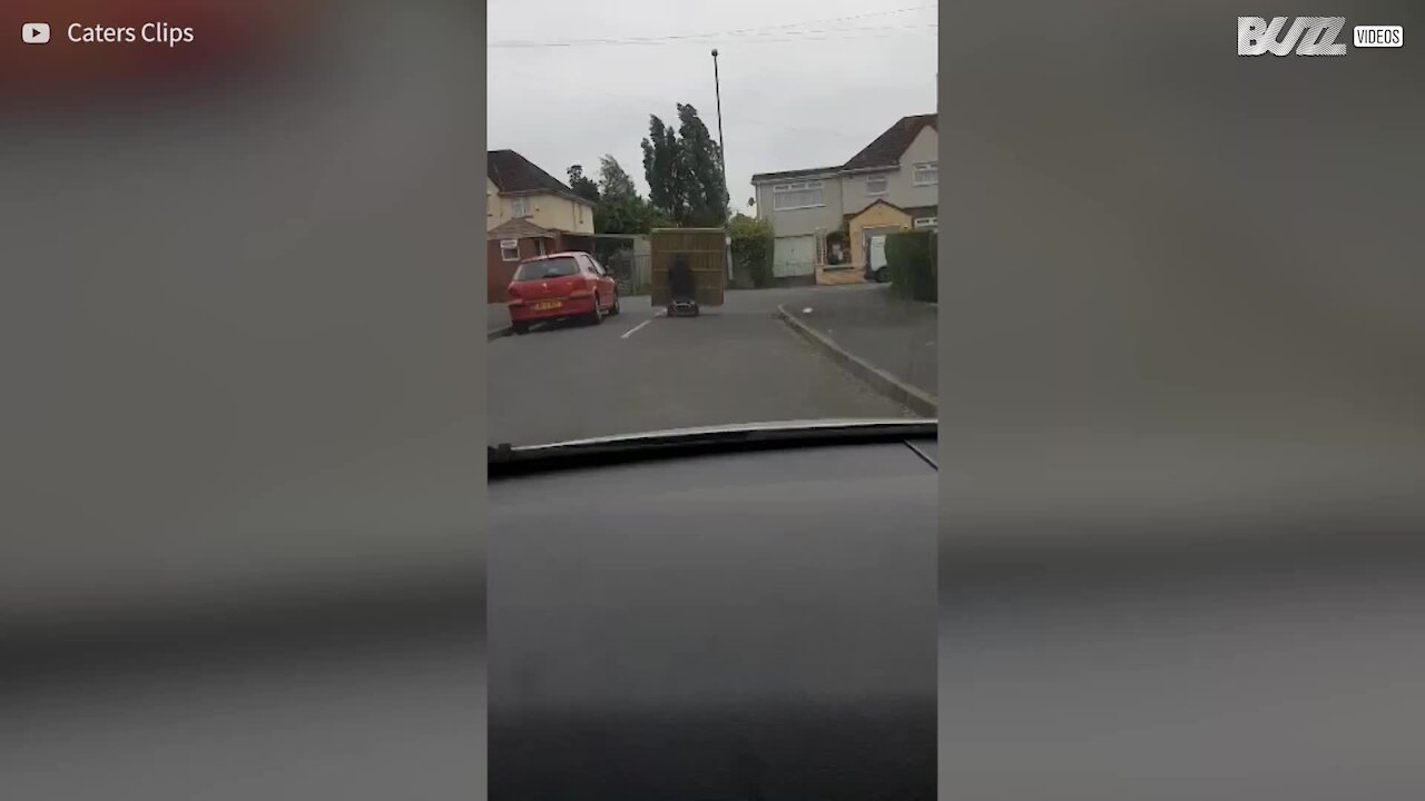 Man balances three wooden panels on mobility scooter