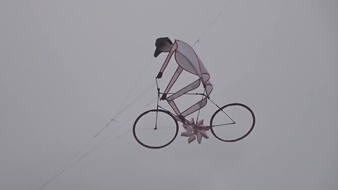 Guy riding bike is the coolest kite ever!