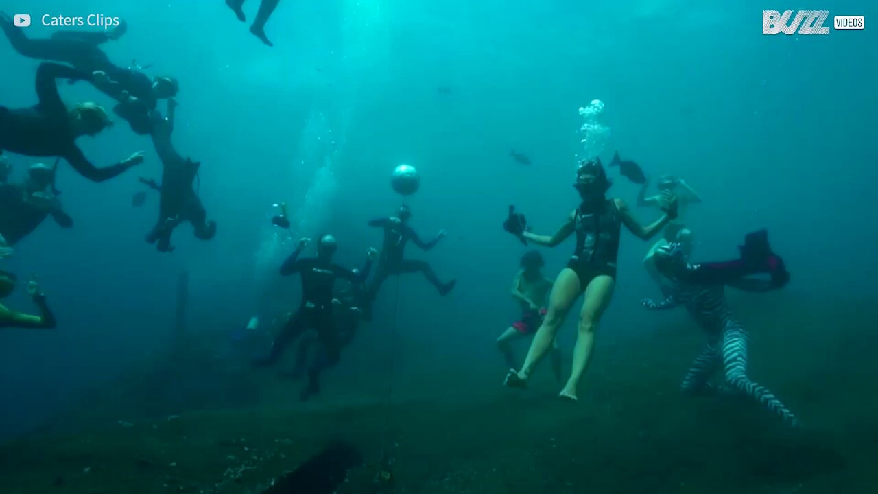 Gruppo di giovani balla sott'acqua, in maschera