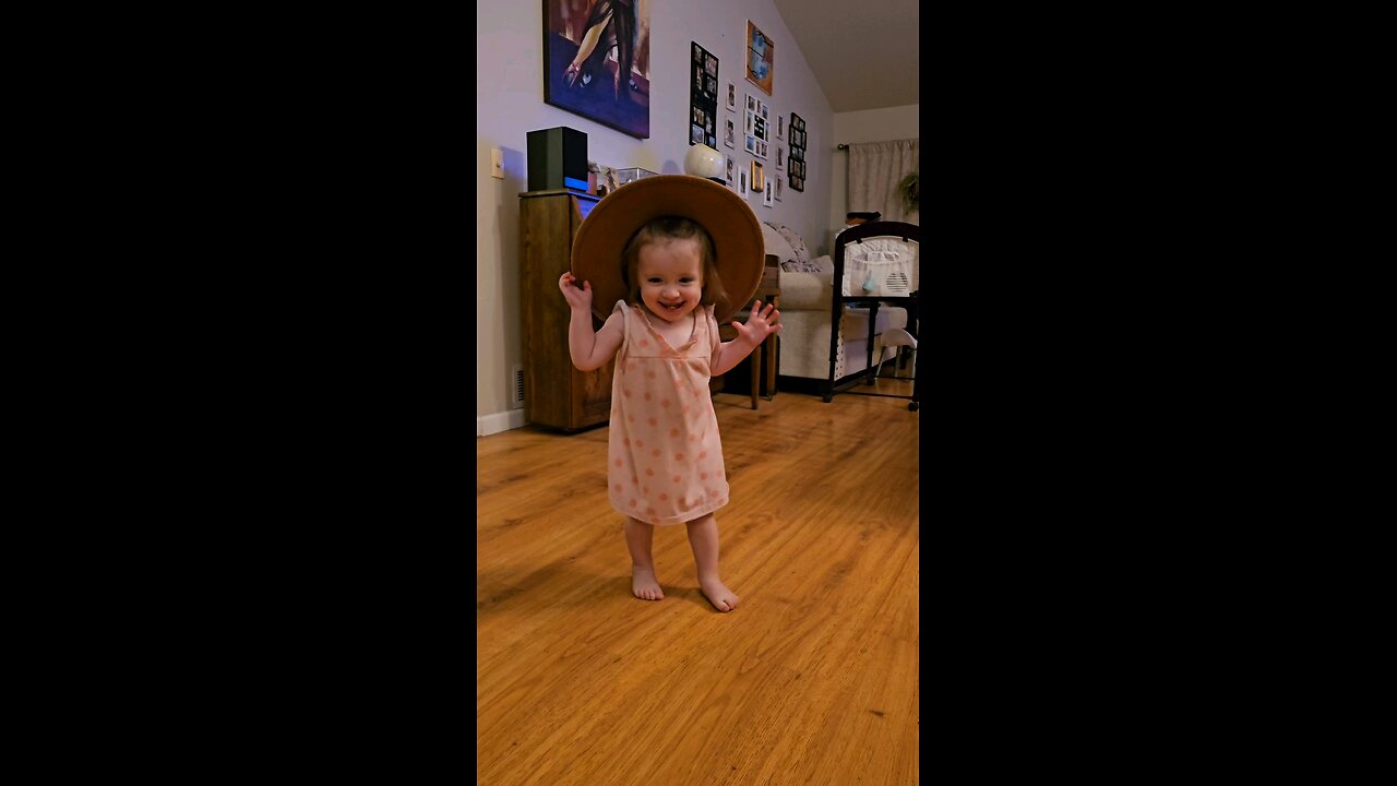 Adorable baby girl wearing mom's hat, dancing and laughing