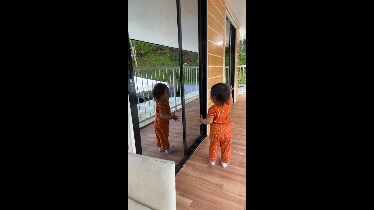 cute baby watching herself in the mirror