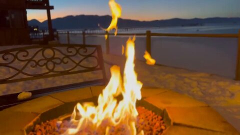 Lake Tahoe beach during sunset; small bonfire in front of a hotel by the beach, in winter.