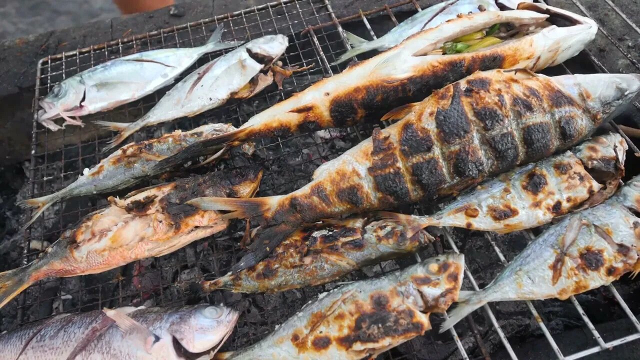 Delicious fresh grilled fish on a grilling tray being cook by charcoal