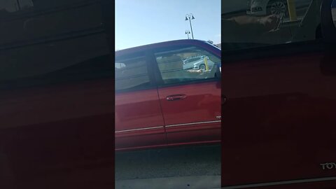 Gang Stalker in red truck parked in an odd spot, with his phone.