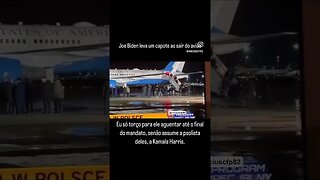 Joe Biden leva um capote ao sair do avião