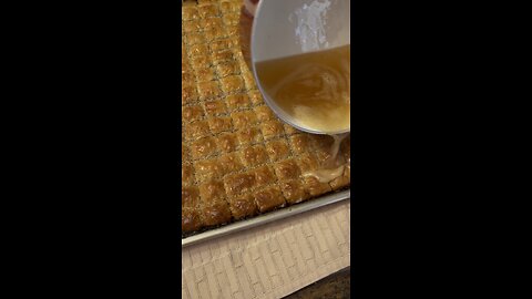 Pouring honey, lemon, butter and sugar over baklava