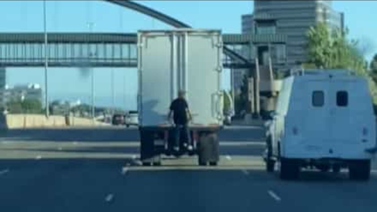 Homem apanha boleia agarrado na traseira de camião